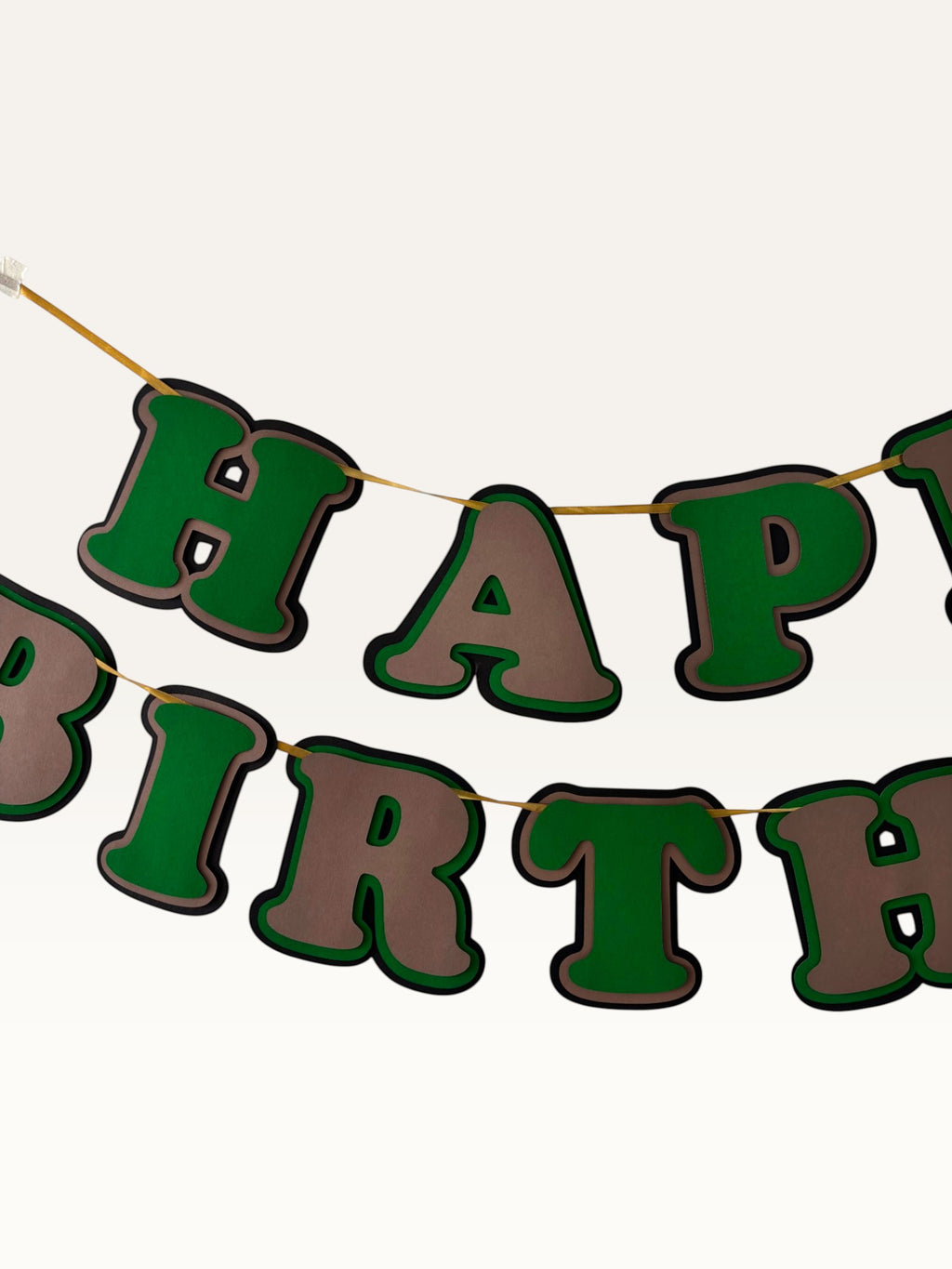 Paper Party Studio layered green and brown paper Happy Birthday banner with dimensional cut-out letters on a cord.
