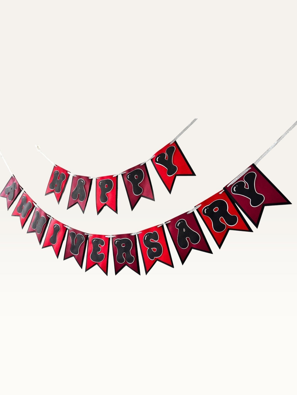Paper Party Studio Happy Anniversary bunting with red swallowtail flags and black bubble letters on silver string.