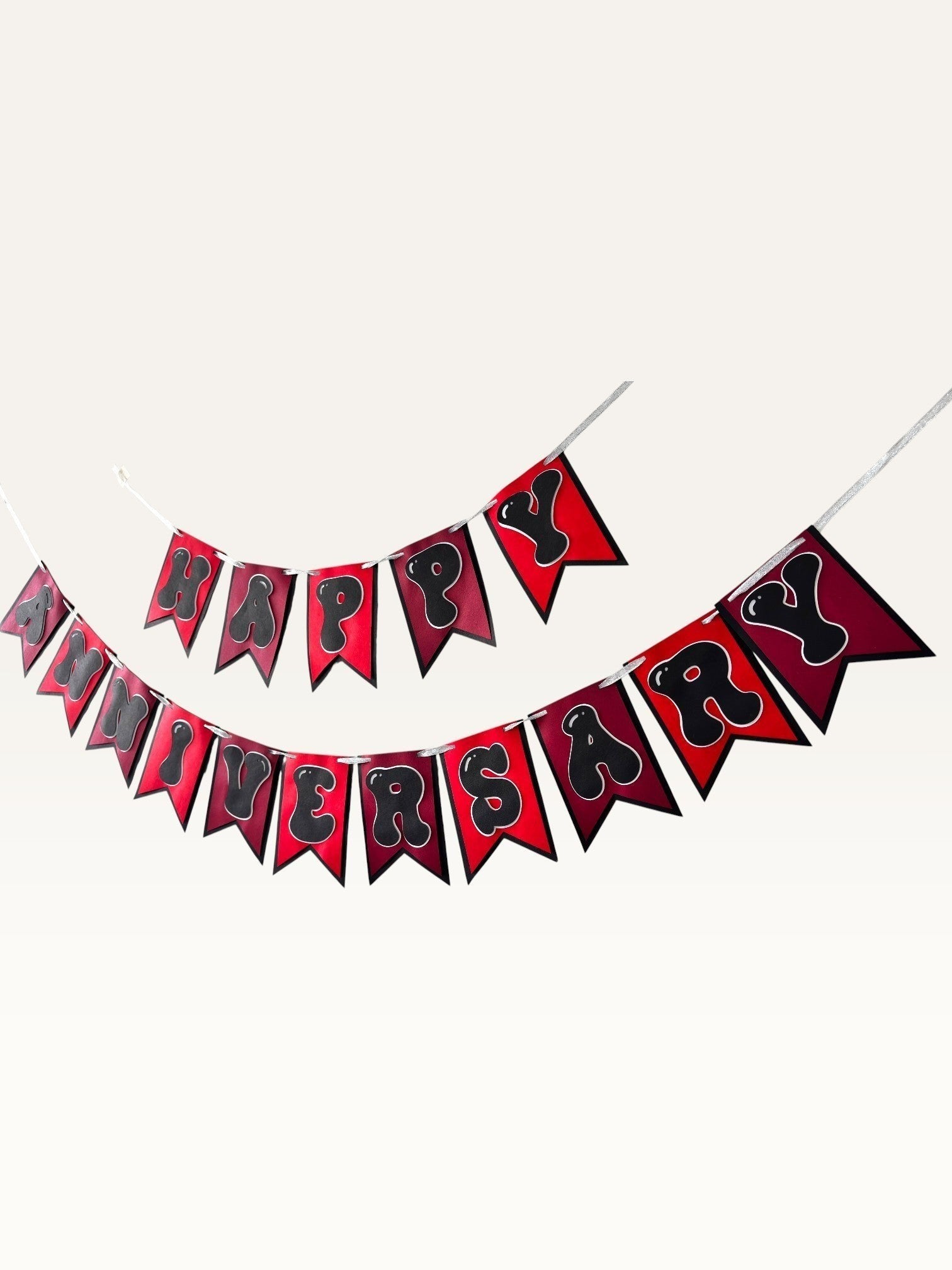 Paper Party Studio Happy Anniversary bunting with red swallowtail flags and black bubble letters on silver string.