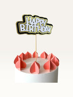 Paper Party Studio layered Happy Birthday cake topper with white lettering, black outline, and gold scalloped backing.