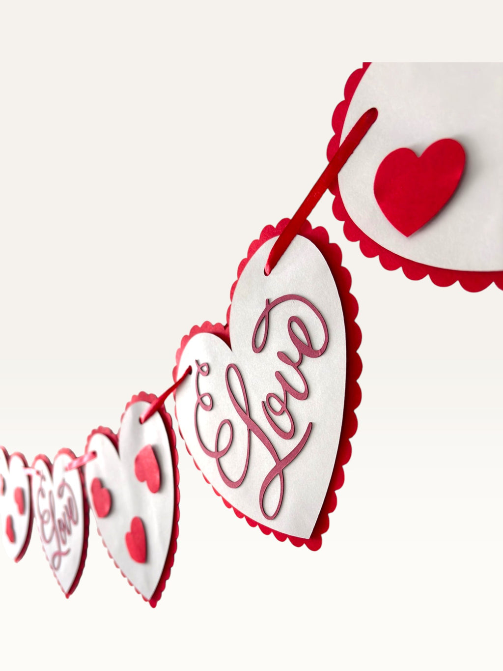 Paper Party Studio Valentine's heart bunting with scalloped white cardstock hearts and red script on a red cord.
