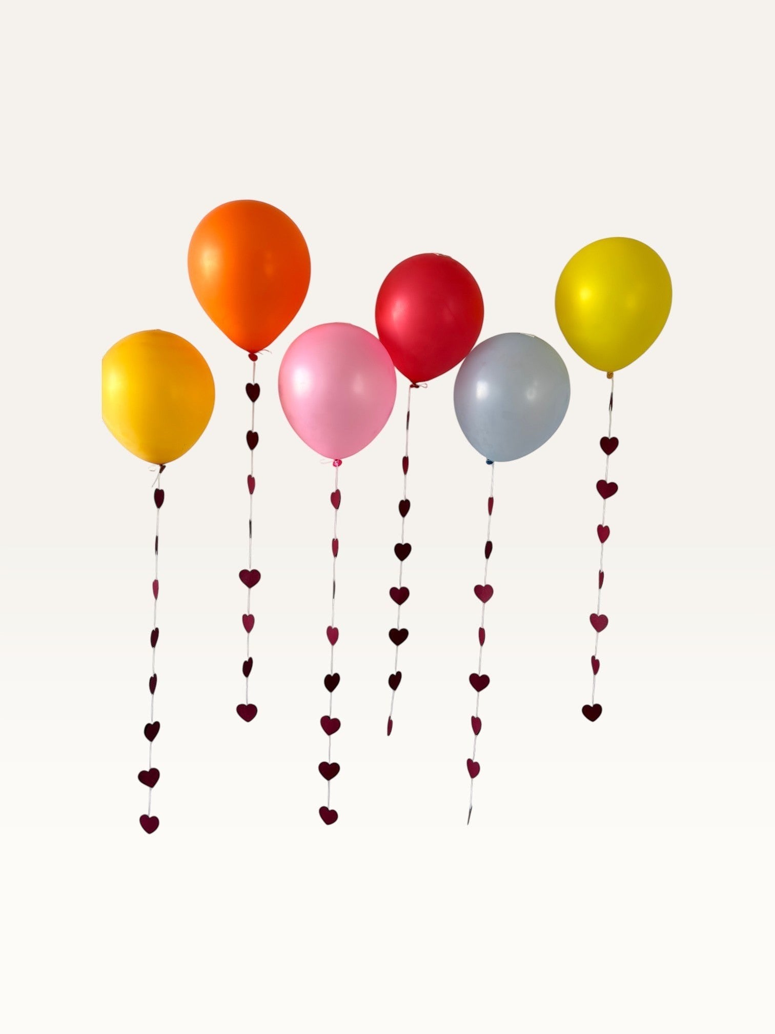 Paper Party Studio heart garland strings hanging from colorful balloons for a romantic wedding or party backdrop.
