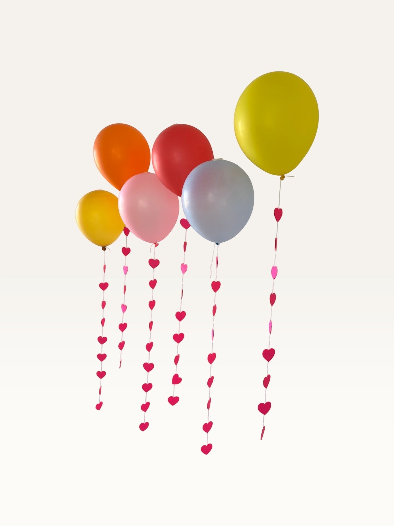 Paper Party Studio heart garland strings hanging from colorful balloons for a romantic party backdrop.