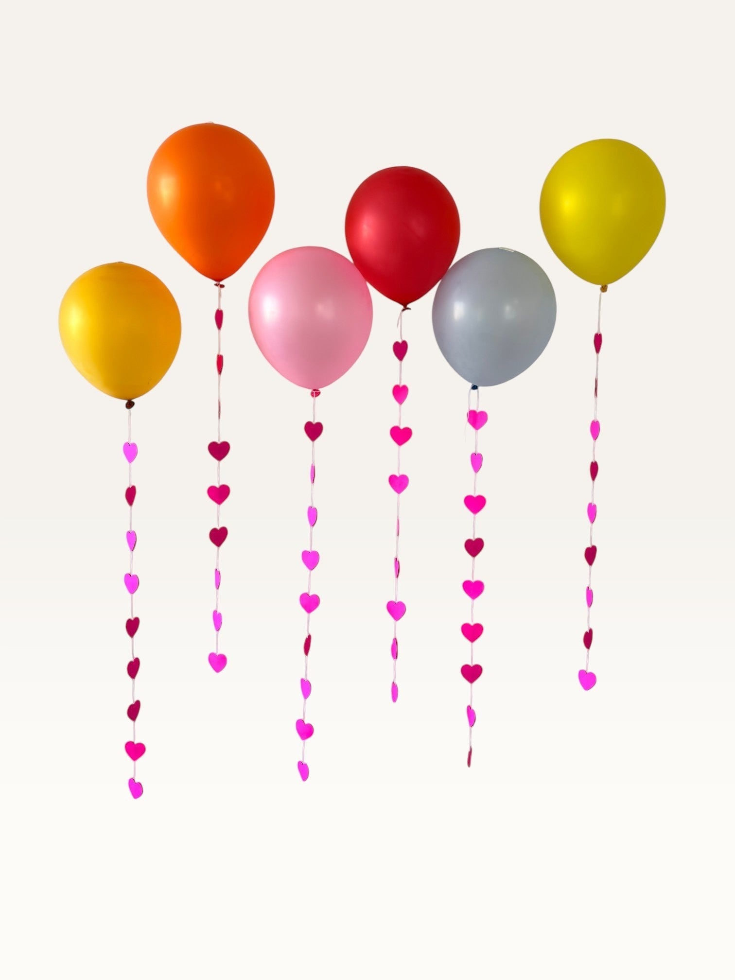 Paper Party Studio heart garland strings hanging from colorful balloons, perfect for romantic event backdrops.