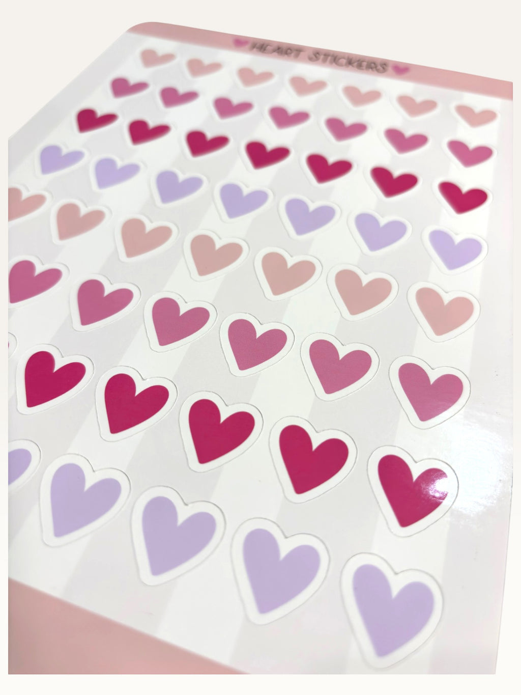 Paper Party Studio glossy kiss-cut sticker sheet featuring rows of pink, red, and lilac heart stickers.