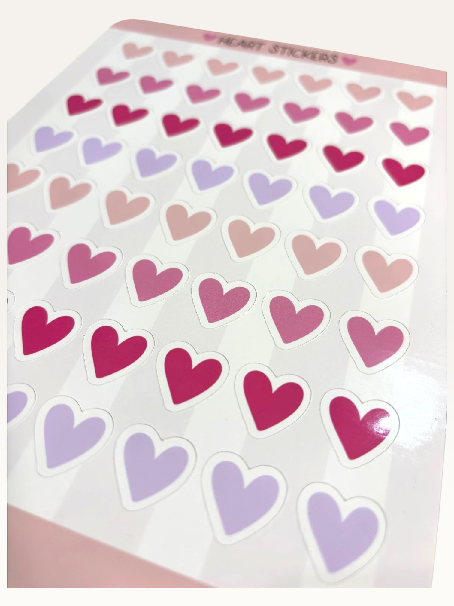 Paper Party Studio glossy kiss-cut sticker sheet featuring rows of pink, red, and lilac heart stickers.