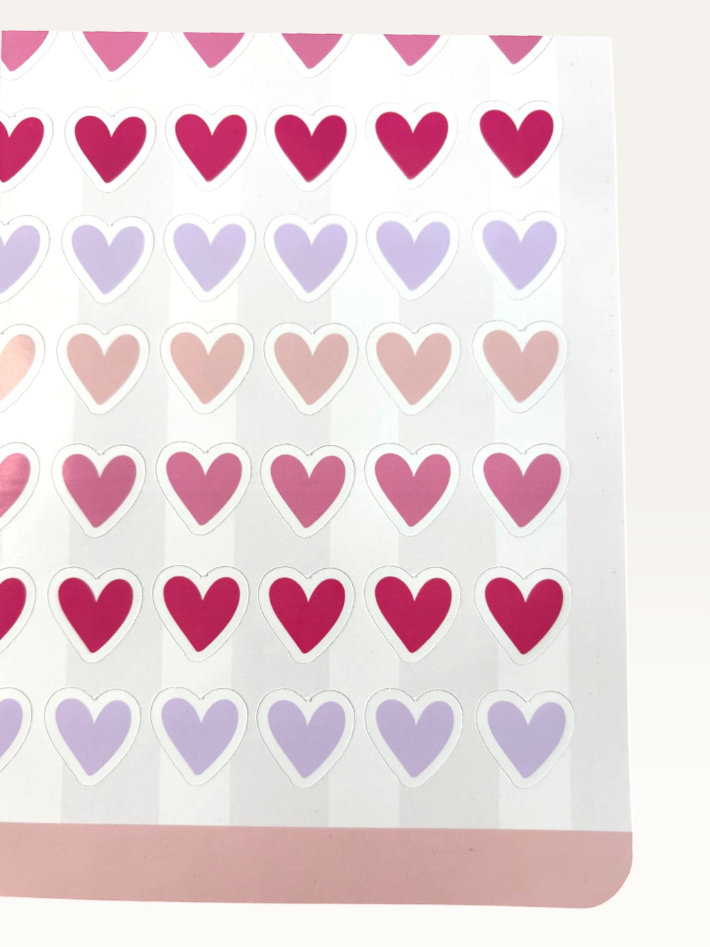 Paper Party Studio glossy heart sticker sheet with rows of pink, red, and lilac hearts on a striped background.