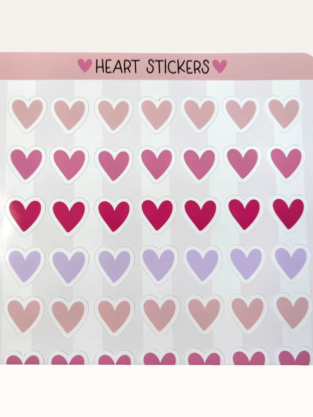 Paper Party Studio glossy heart sticker sheet with rows of pink, red, and lilac hearts on a striped background.