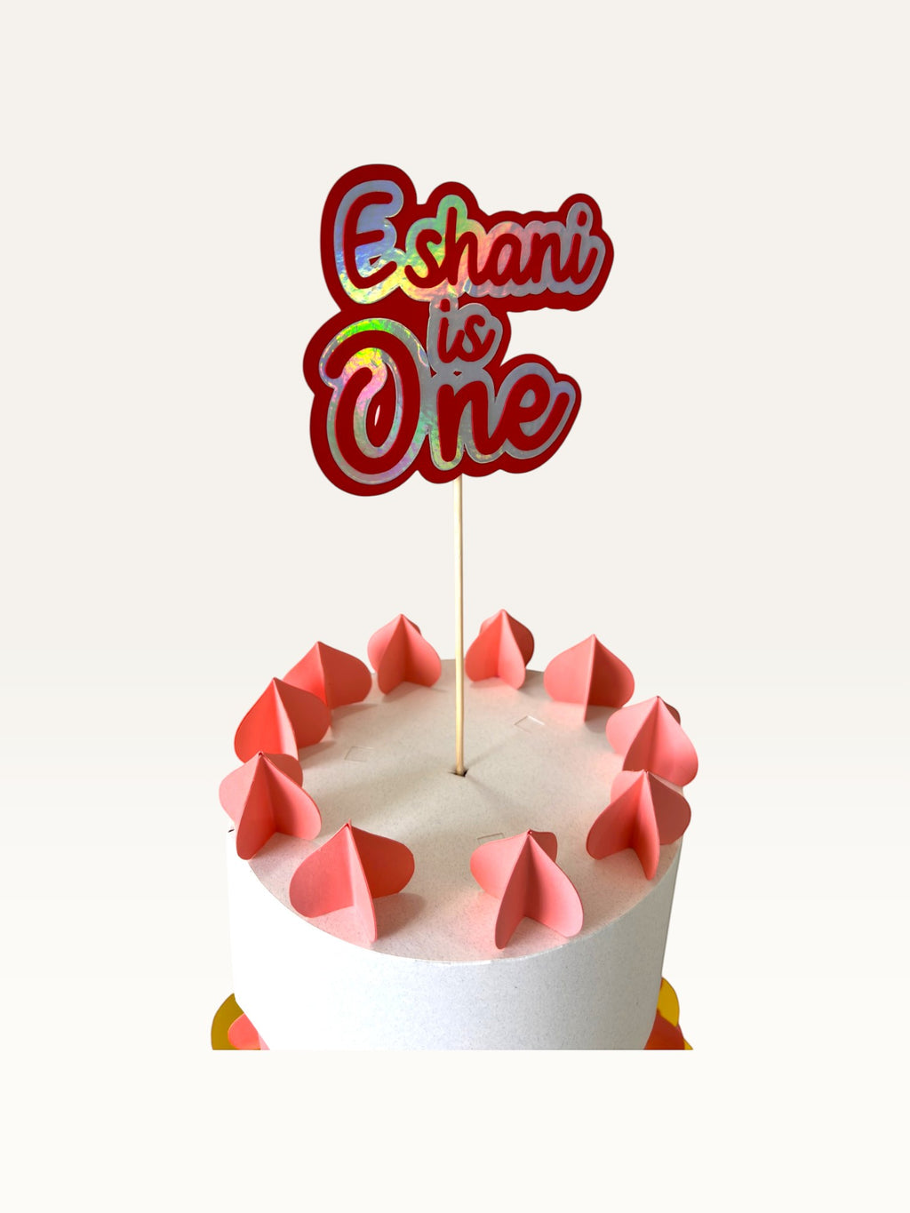 Paper Party Studio personalised holographic script cake topper reading Eshani is One on a white cake with pink hearts