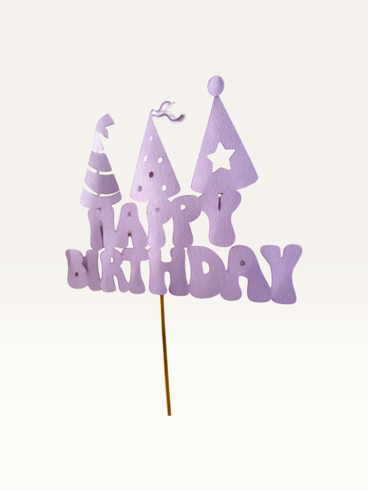 Paper Party Studio lavender Happy Birthday cake topper with three party hat cut-outs on a wooden pick.