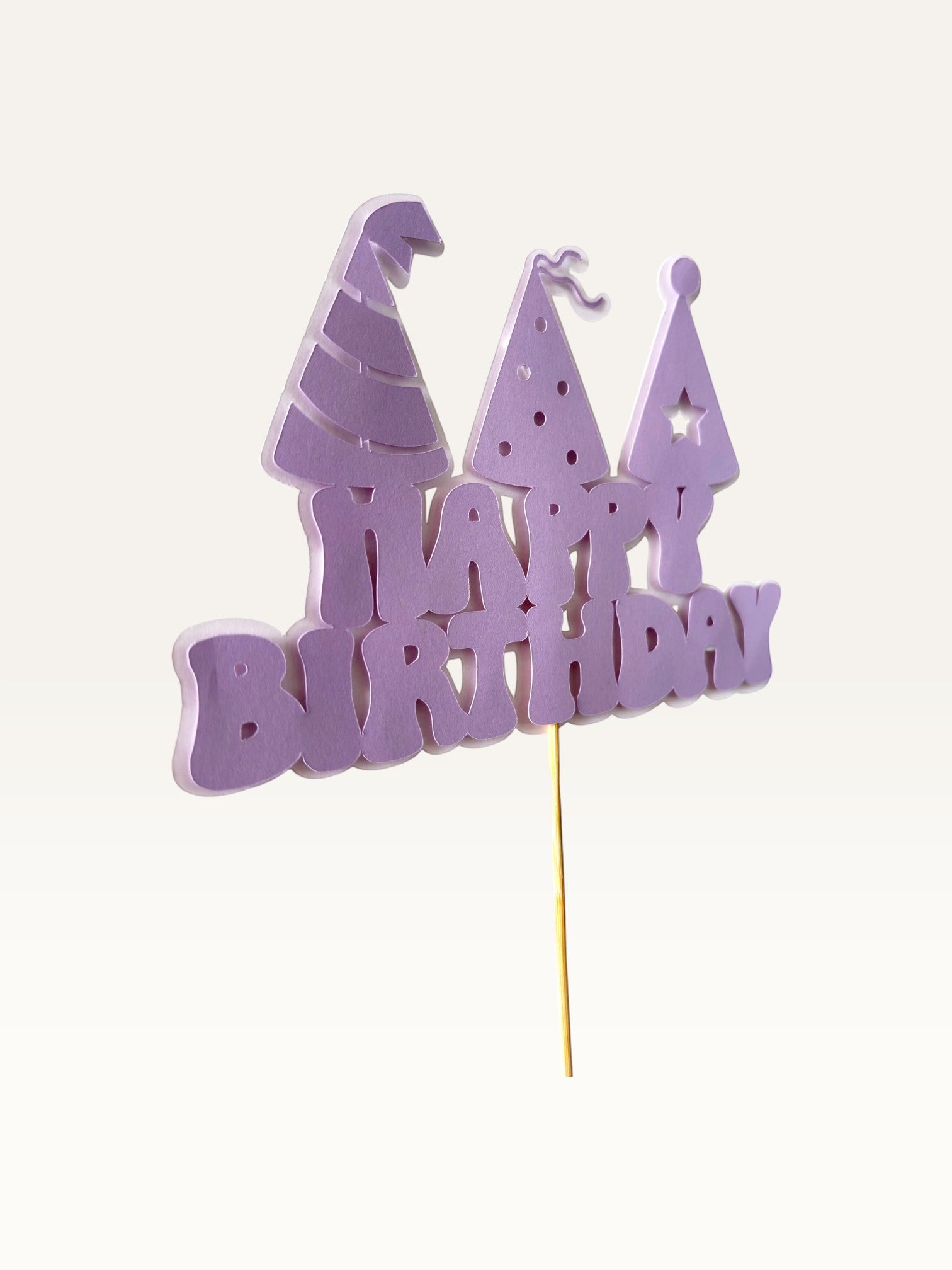 Paper Party Studio lavender Happy Birthday cake topper with three party hat cut-outs on a wooden pick