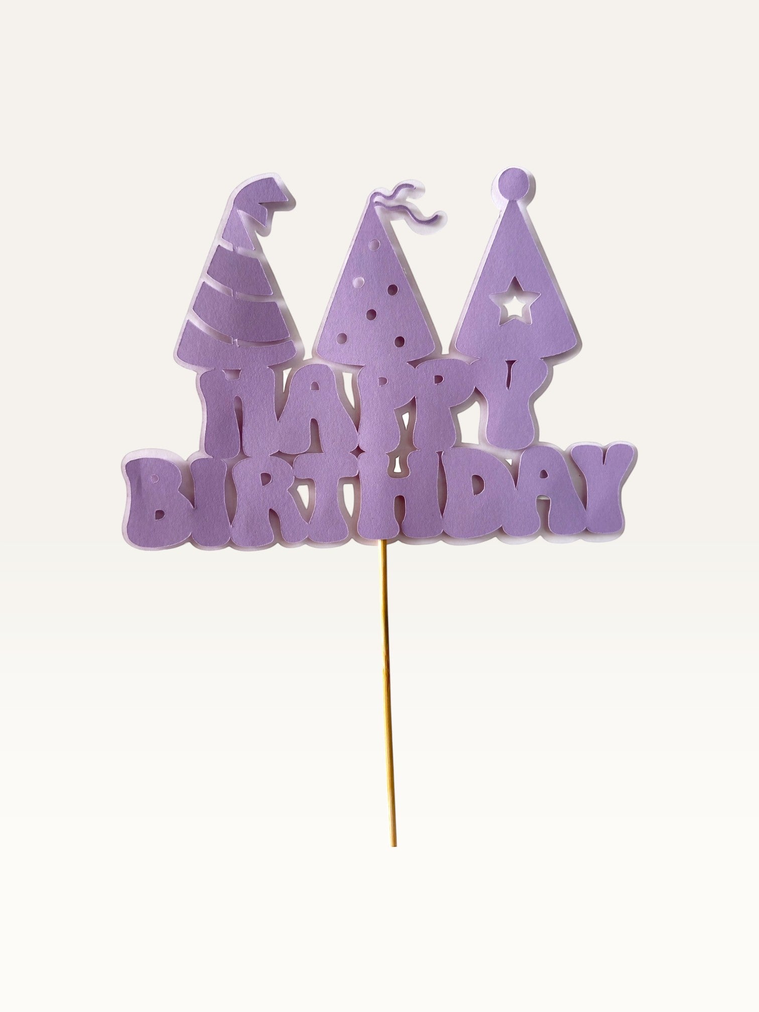 Paper Party Studio lavender Happy Birthday cake topper with three party hat cut-outs on a wooden pick.
