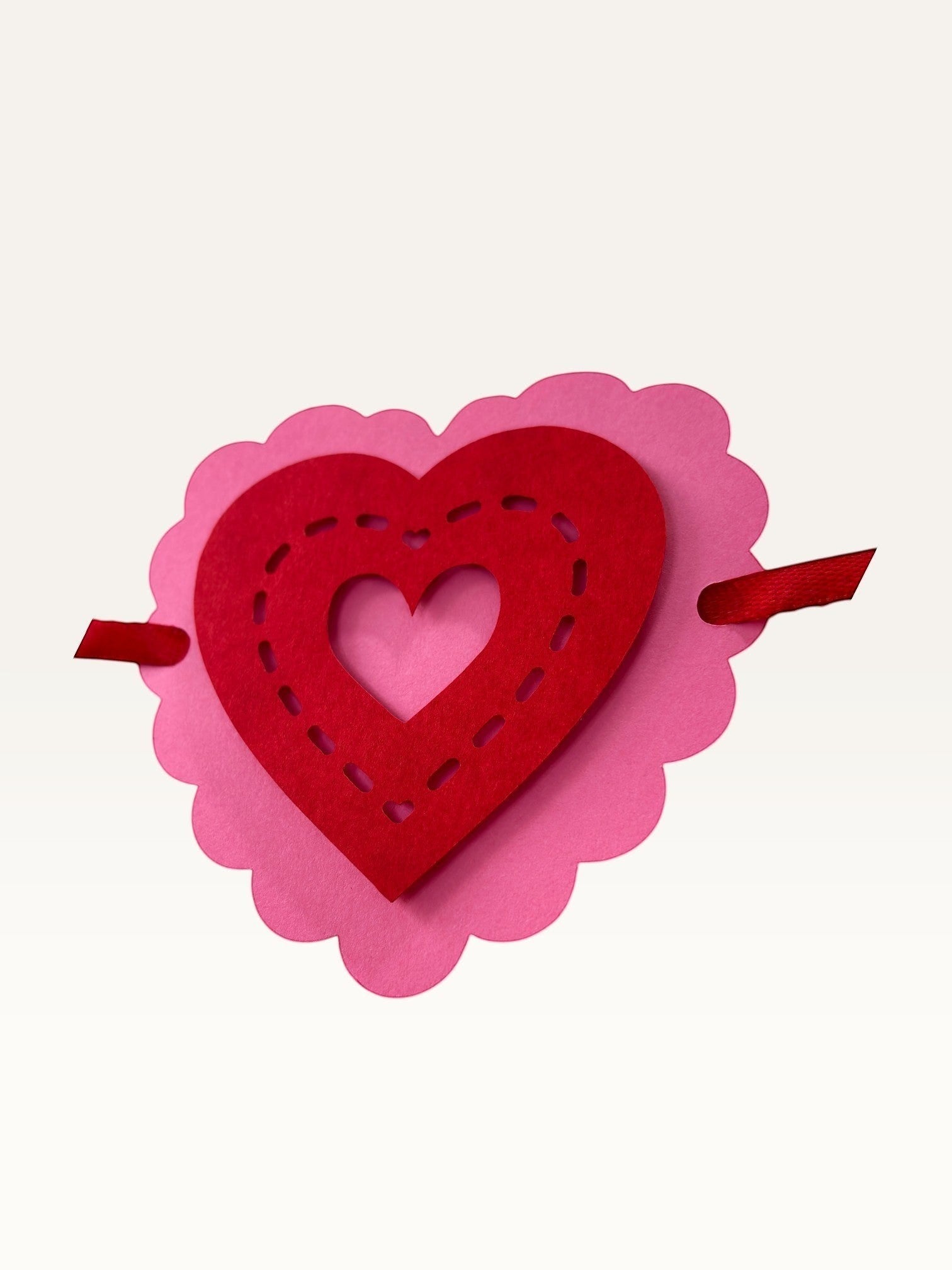 Paper Party Studio layered heart garland with pink scalloped and red stitched-effect cardstock hearts on a ribbon.