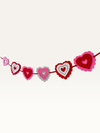 Paper Party Studio layered heart garland with scalloped pink, red, and white cardstock hearts and stitched details.