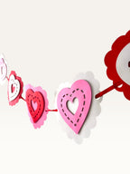 Paper Party Studio layered heart garland featuring scalloped pink, red, and white cardstock hearts with stitched detail.