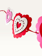 Paper Party Studio layered heart garland featuring scalloped pink, red, and white cardstock hearts with stitched details.