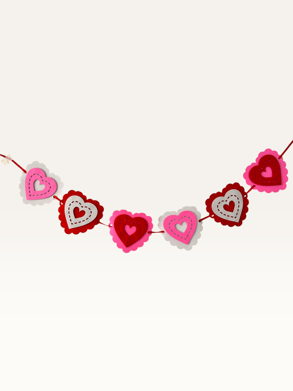 Paper Party Studio layered heart garland featuring scalloped pink, red, and white cardstock hearts with stitched details.