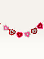 Paper Party Studio layered heart garland featuring scalloped pink, red, and white cardstock hearts with stitched details.