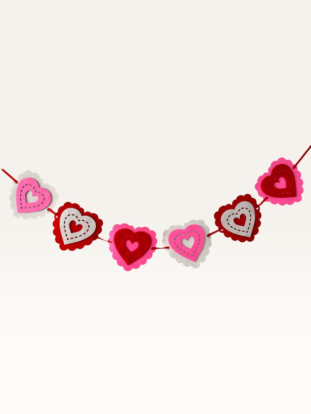 Paper Party Studio layered heart garland featuring scalloped pink, red, and white cardstock hearts with stitched details.