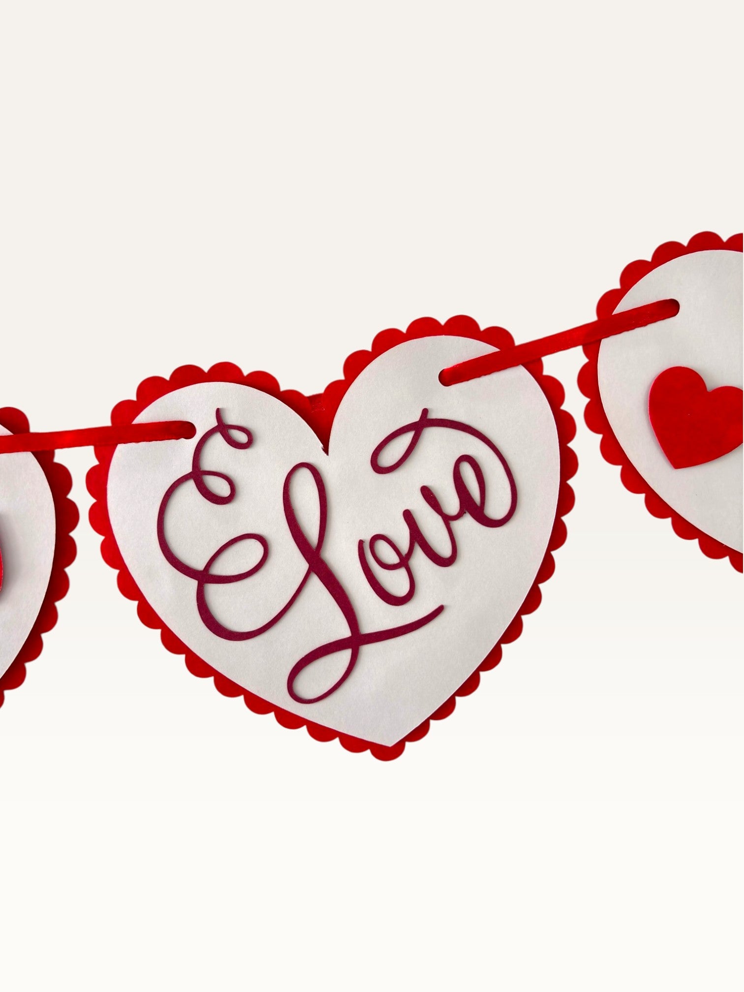 Paper Party Studio heart bunting with scalloped white cardstock hearts and red script Love text on a red cord.