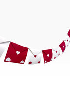 Paper Party Studio red and white envelope bunting with heart cut-outs on silver cord.