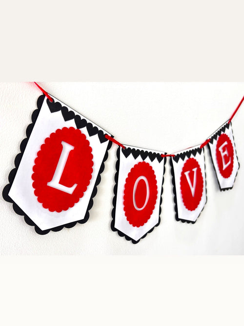 Paper Party Studio LOVE banner with red scalloped medallions, white flags, and black heart trim for romantic events.