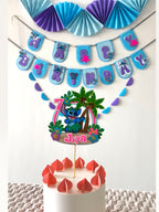 Paper Party Studio tropical luau birthday set with blue alien cake topper, banner, and paper fans in blue and purple.