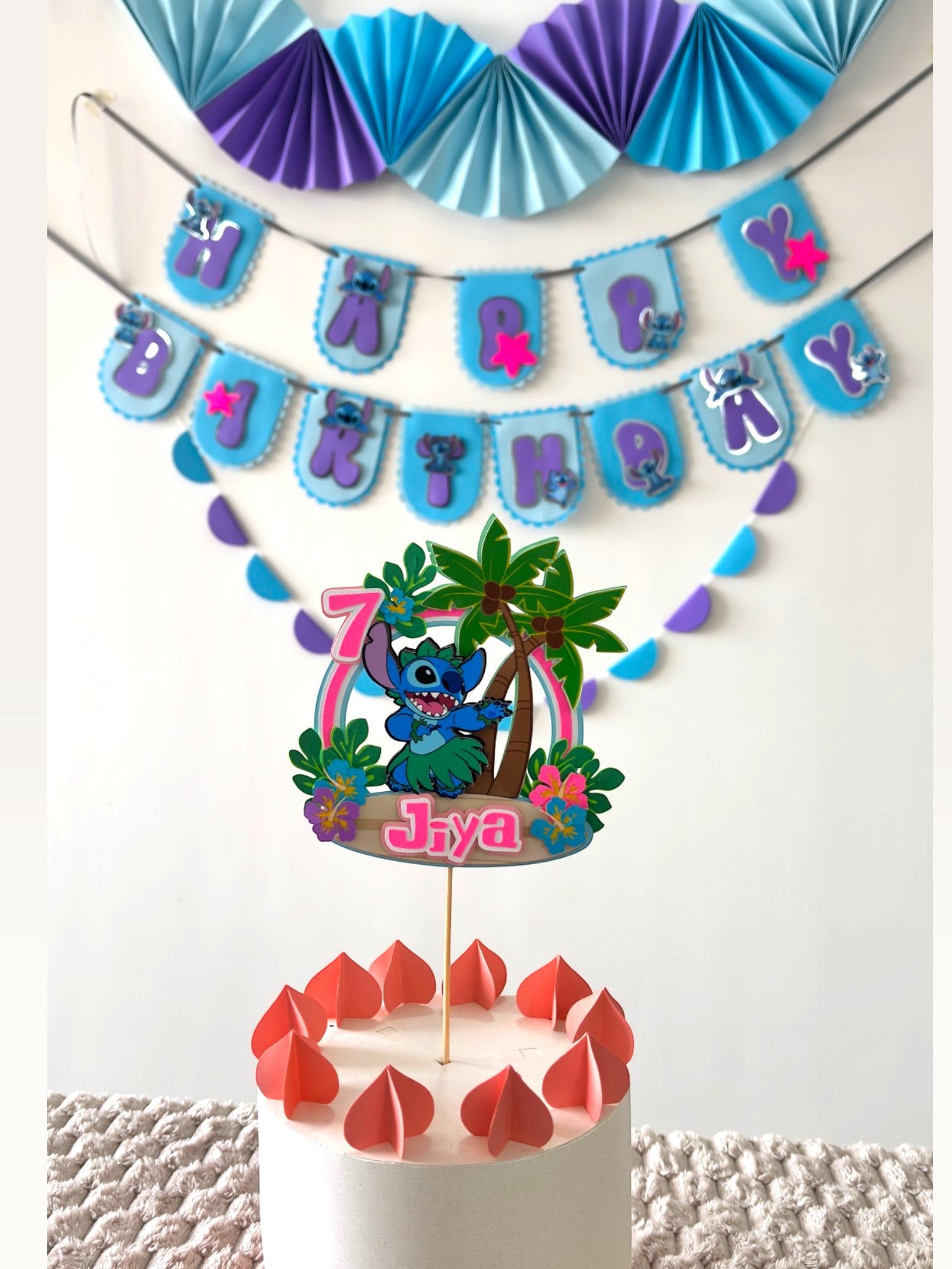 Paper Party Studio tropical luau birthday set with blue alien cake topper, banner, and paper fans in blue and purple.