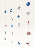 Paper Party Studio under the sea hanging backdrop with cardstock mermaid tails, shells, and seahorses in pink and blue.