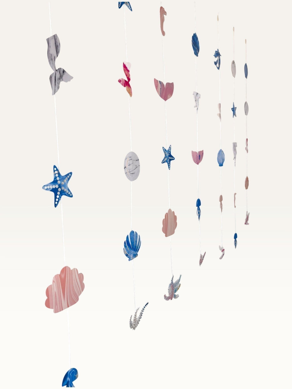 Paper Party Studio under the sea hanging backdrop with pink and blue cardstock mermaid tails, shells, and starfish.