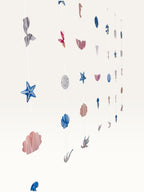 Paper Party Studio under the sea hanging backdrop with pink and blue cardstock mermaid tails, shells, and starfish.