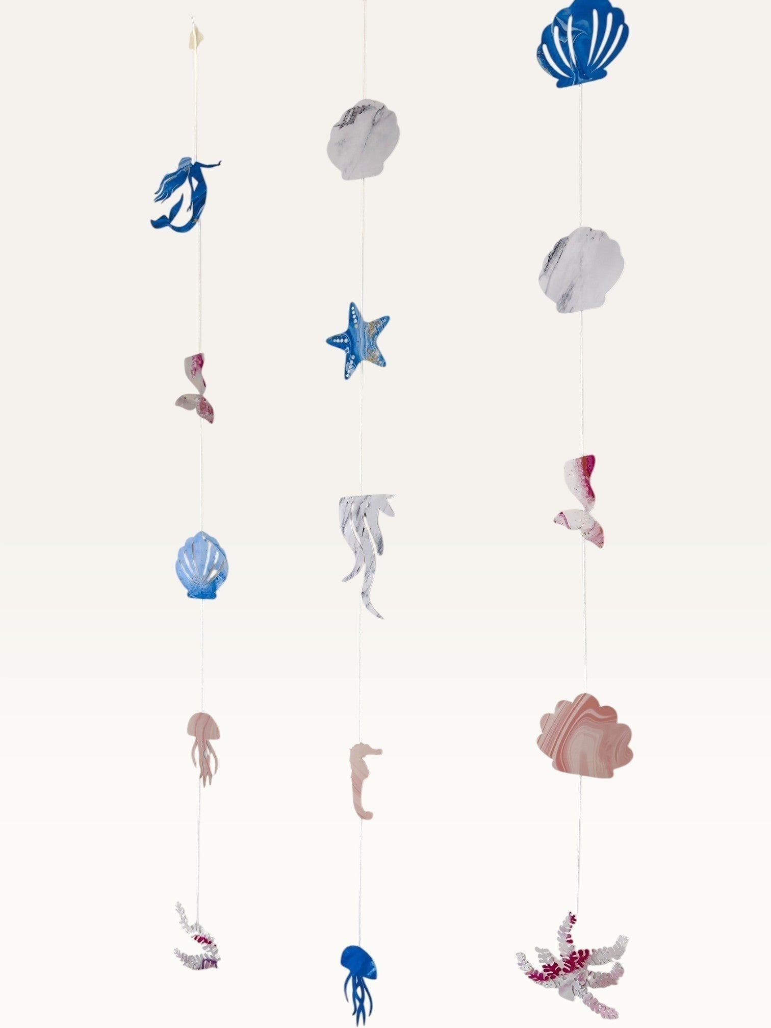 Paper Party Studio under the sea hanging backdrop with pink and blue cardstock mermaid, shell, and starfish shapes.