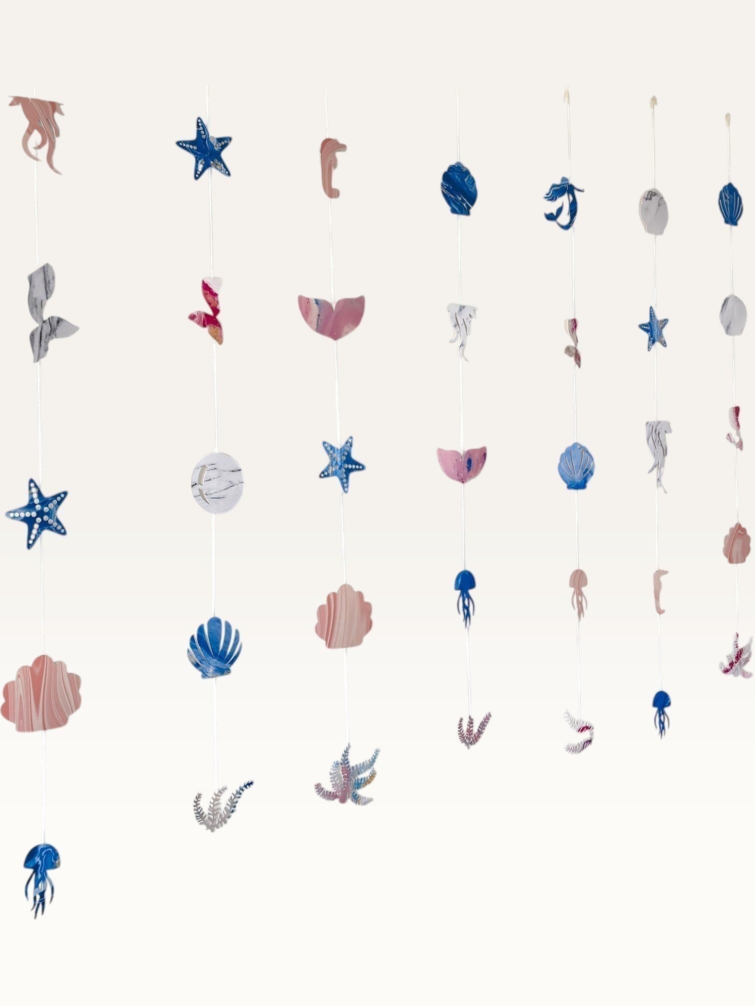 Paper Party Studio under the sea hanging backdrop with pink and blue mermaid, shell, and starfish cardstock cutouts.