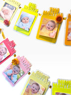 Paper Party Studio monthly milestone photo banner with 13 frames in sunset colors, each with a paper rosette accent.