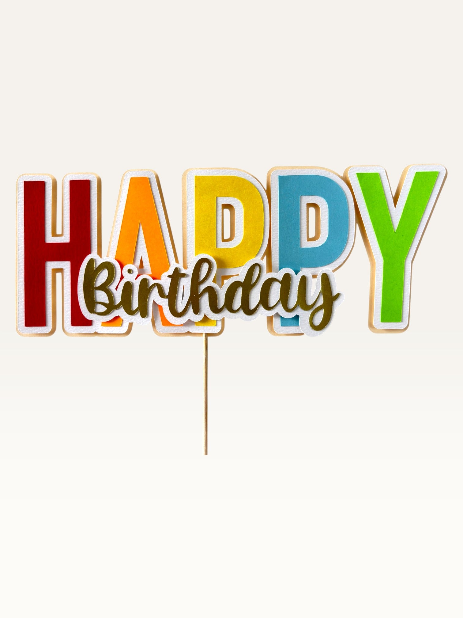 Paper Party Studio multicolour block letter Happy Birthday cake topper with gold script and white outline on a pick