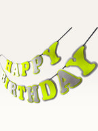 Paper Party Studio neon yellow and grey layered paper Happy Birthday banner strung on a cord for party decoration.