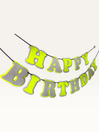 Paper Party Studio neon and grey layered paper Happy Birthday banner with bold cut-out letters on a hanging cord.