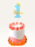 Paper Party Studio personalized blue number one cake topper with a gold crown and name on a decorated cake