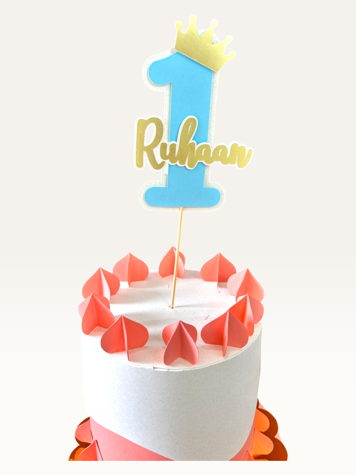 Paper Party Studio personalized blue number one cake topper with a gold crown and name on a decorated cake