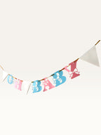 Paper Party Studio Oh Baby banner with pink and blue paper letters featuring bow cut-outs and white triangle pennants.