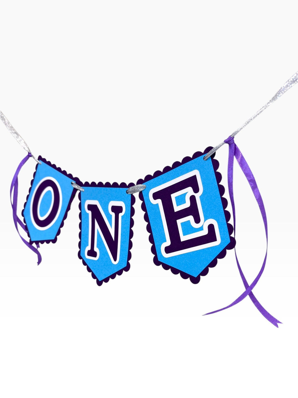 Paper Party Studio blue scalloped banner spelling ONE with purple ribbon ties, perfect for a first birthday cake smash.