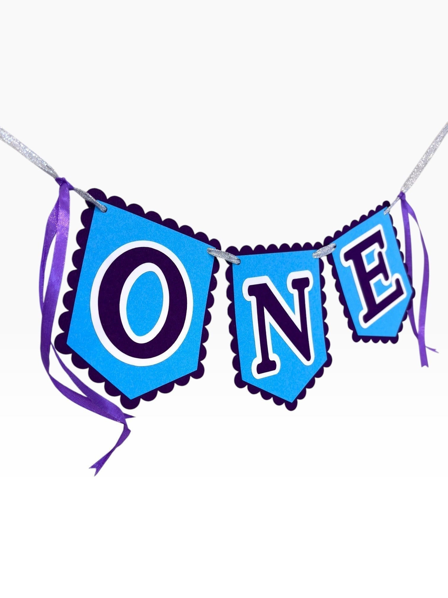 Paper Party Studio blue scalloped banner spelling ONE with purple ribbon ties, perfect for a first birthday cake smash.