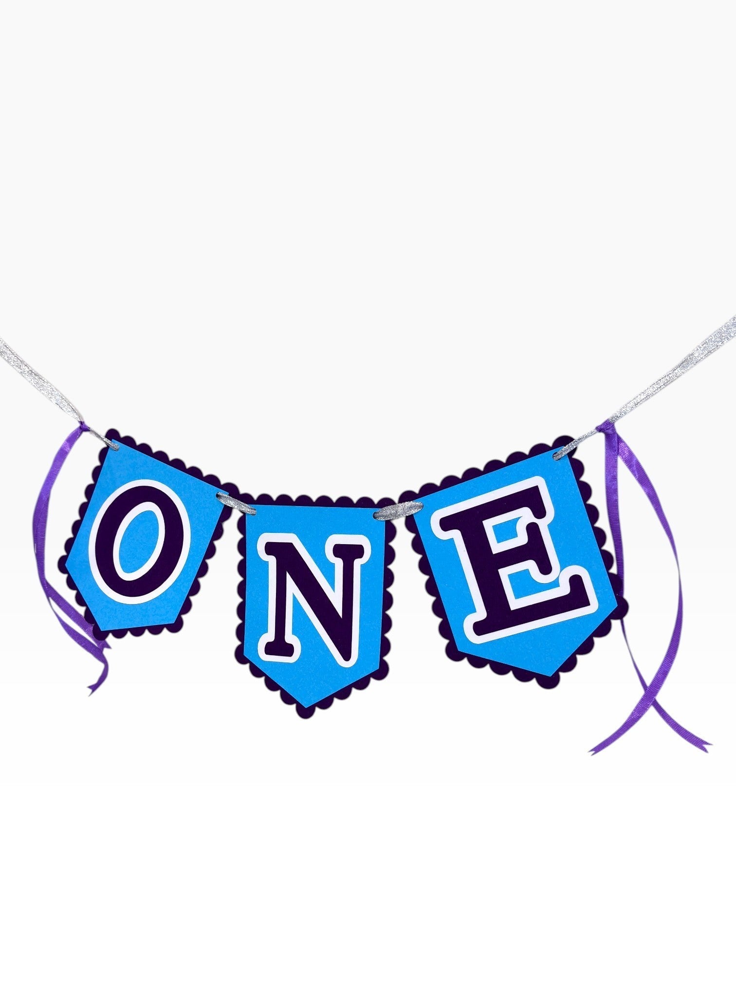 Paper Party Studio blue scalloped paper banner spelling "ONE" with purple ribbon ties, perfect for a first birthday cake smash.