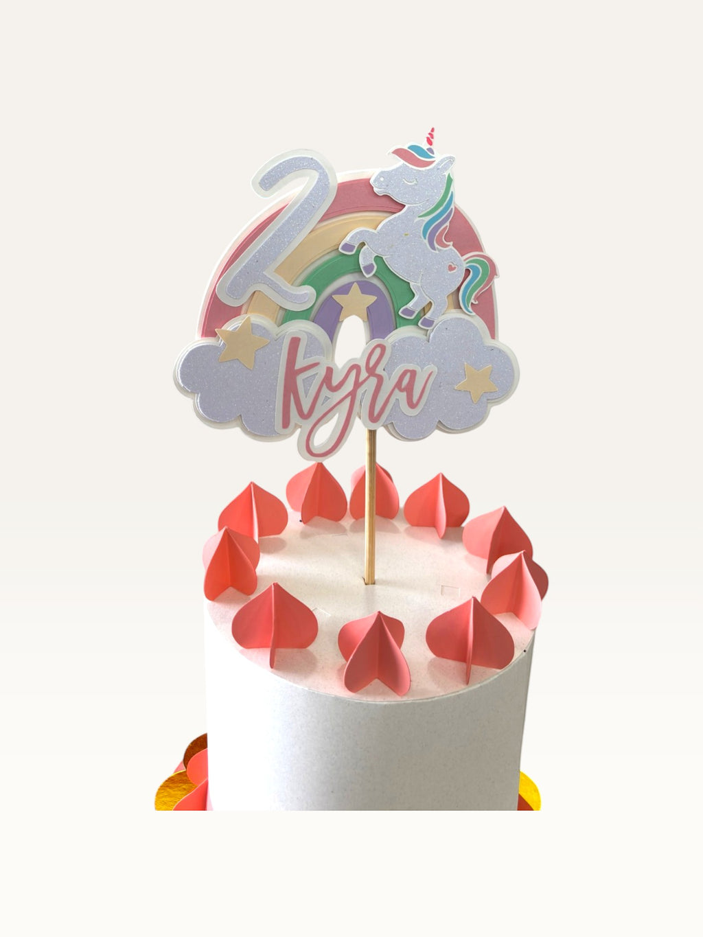 Paper Party Studio personalised unicorn cake topper with rainbow, clouds, name, and age on a white birthday cake