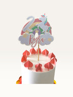 Paper Party Studio personalised unicorn cake topper with rainbow, clouds, name, and age on a white birthday cake