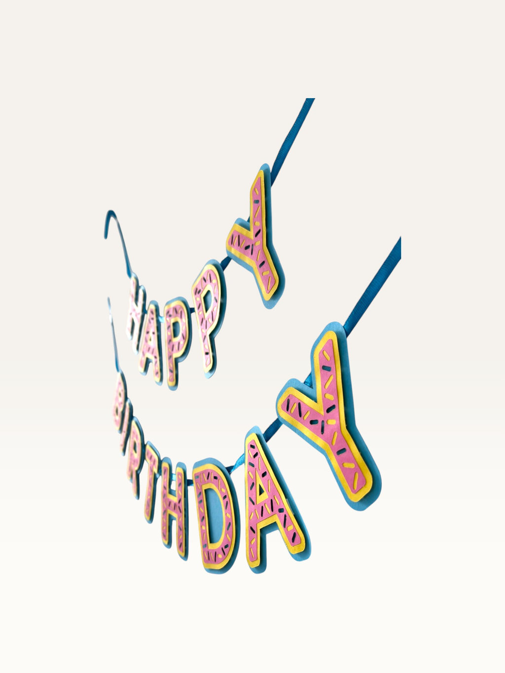 Paper Party Studio pink donut-glaze Happy Birthday paper bunting banner with candy sprinkle details on blue string