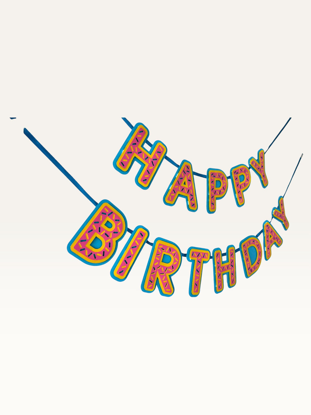 Paper Party Studio Happy Birthday banner in pink donut-glaze style with candy sprinkle details and yellow outlines.