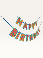 Paper Party Studio Happy Birthday banner in pink donut-glaze style with candy sprinkle details and yellow outlines.