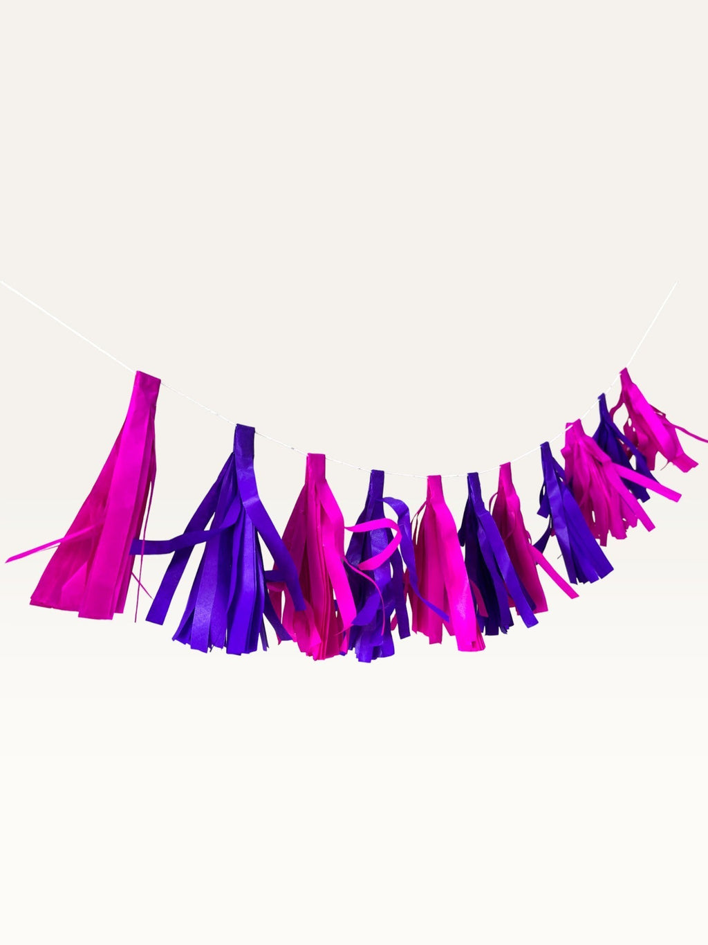 Paper Party Studio handmade tissue paper tassel garland in vibrant pink and purple for party decorations.