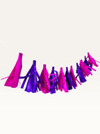 Paper Party Studio handmade tissue paper tassel garland in vibrant pink and purple for party decorations.